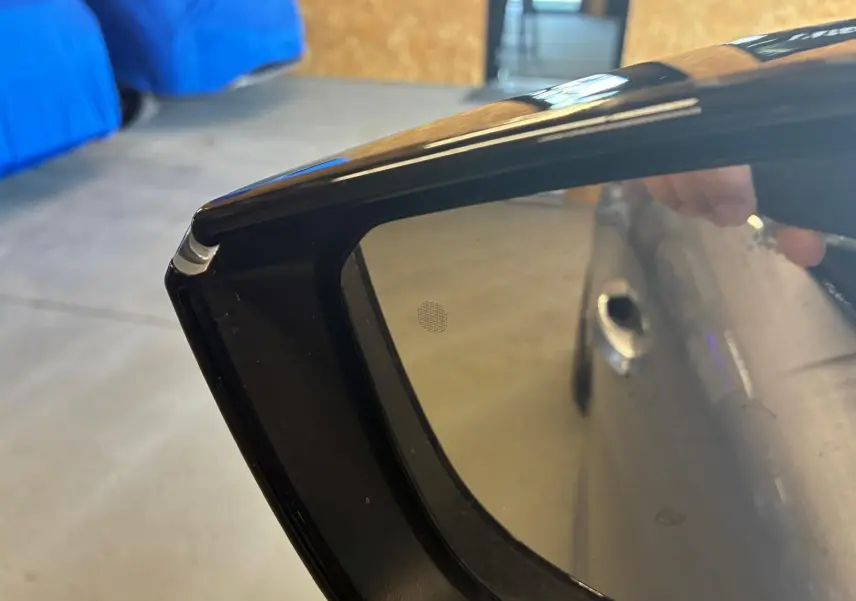 Détail du rétroviseur extérieur noir de la Peugeot 308 gris, avec reflet partiel de la portière côté droit.