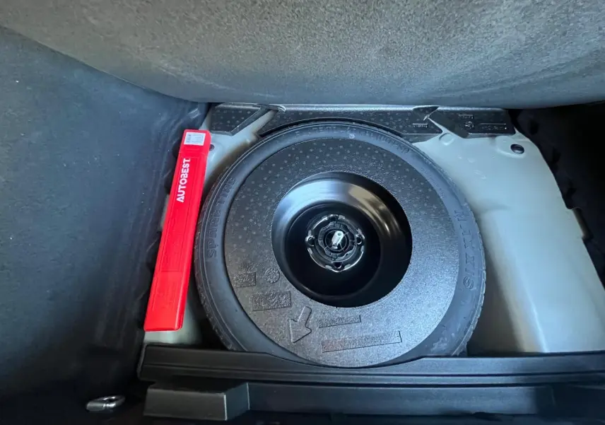 Gros plan sur la roue de secours et le triangle de signalisation rouge dans le coffre du DS3 Crossback Performance Line gris.