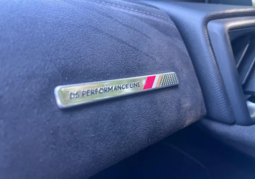 Gros plan sur le badge DS PERFORMANCE Line sur la planche de bord en tissu noir du DS3 Crossback 2022.