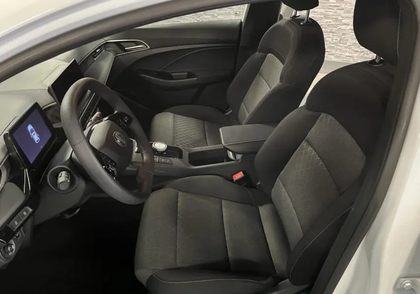 Vue intérieure côté conducteur de la MG3 1.5 Hybrid+ 195 Comfort 2024 avec sièges tissu noir et écran tactile central.