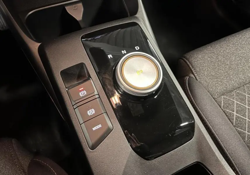 Gros plan sur la console centrale noire de la MG3 1.5 Hybrid+ 195 Comfort avec sélecteur rotatif de boîte auto et boutons de contrôle.