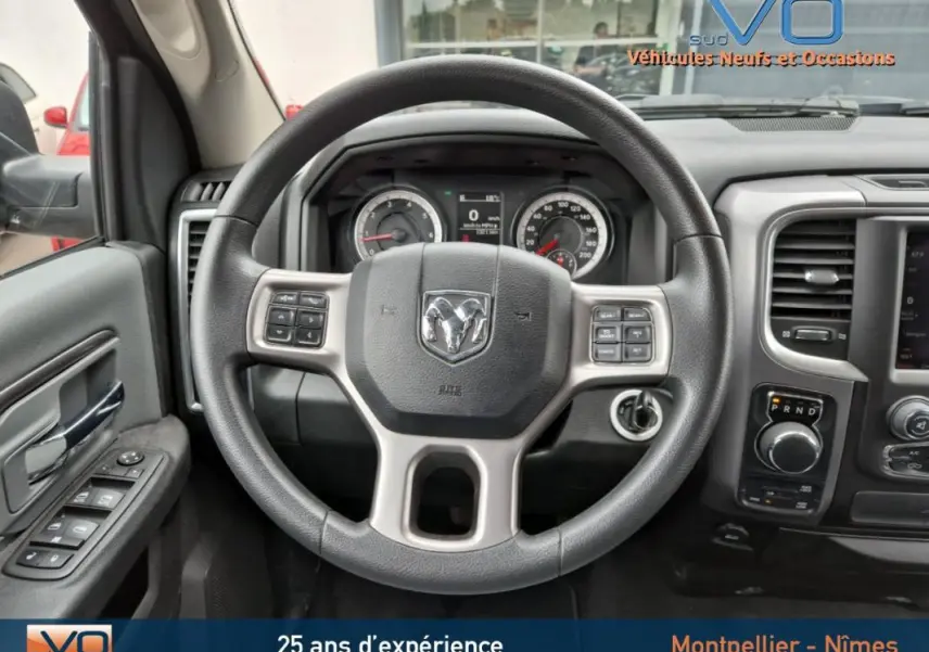 Vue intérieure centrée sur le volant du Dodge RAM Crew SLT Classic Black Package gris foncé, tableau de bord et commandes visibles.