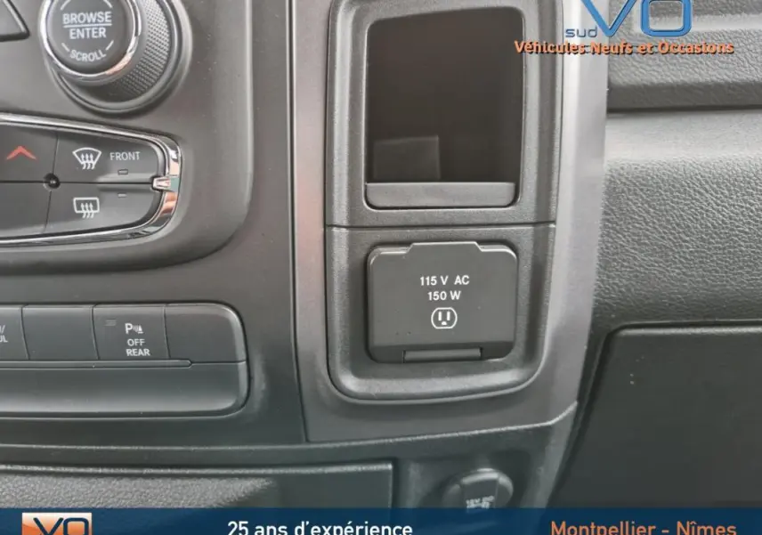 Gros plan sur la console centrale du Dodge RAM Crew SLT Classic Black Package 2022, montrant une prise 115V et commandes climatisation.