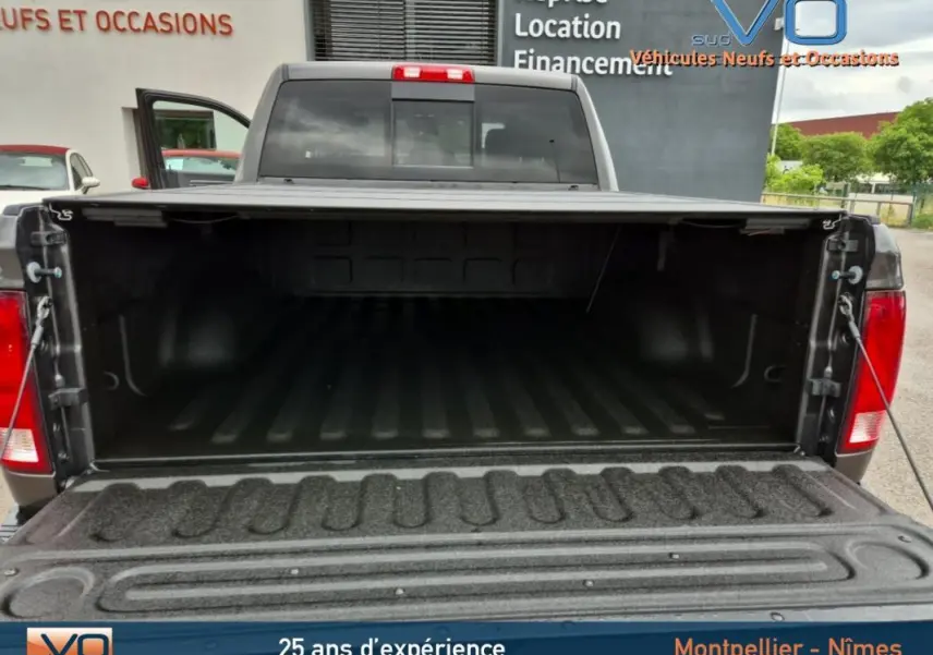 Vue arrière du Dodge RAM Crew SLT Classic Black Package gris foncé 2022 avec la benne ouverte, montrant l'espace de chargement vide.