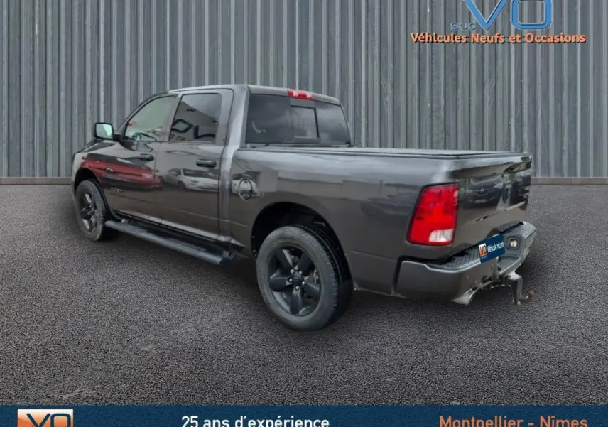 Vue 3/4 arrière droite d'un Dodge RAM Crew SLT Classic Black gris foncé avec jantes noires et attelage, 2022.