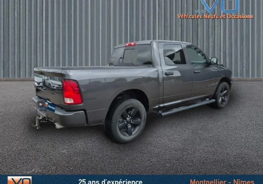 Vue 3/4 arrière droite d'un Dodge RAM Crew SLT Classic Black Package gris foncé avec jantes noires et attelage.