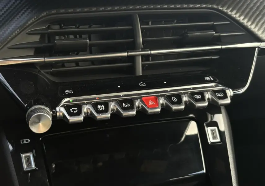 Gros plan sur la console centrale noire brillante du Peugeot 2008 Hybrid 145 e-DSC6 Allure avec boutons métallisés et écran tactile éteint.