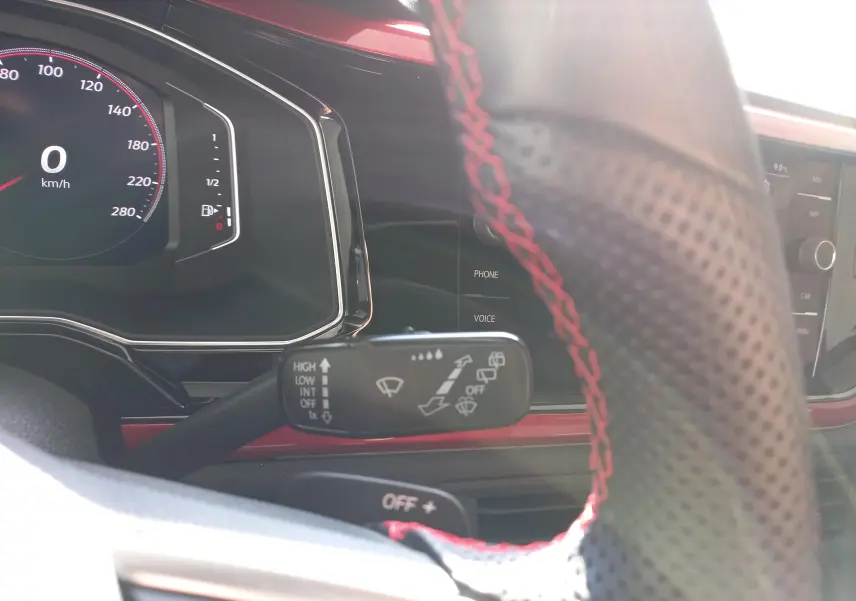 Vue rapprochée du tableau de bord et du volant perforé avec surpiqûres rouges de la Volkswagen Polo GTI 2024.