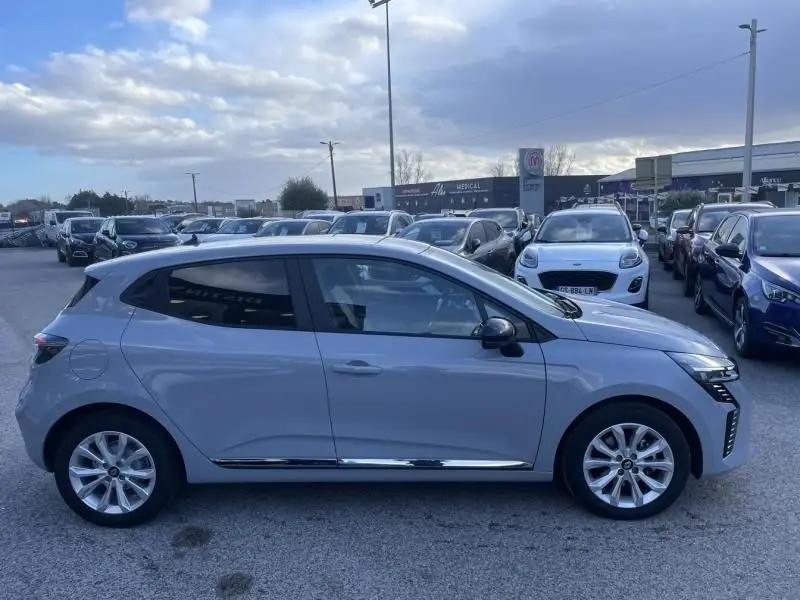 Profil côté gauche d'une Renault Clio V gris métal 2025, version DCI 100 Evolution, garée en extérieur.