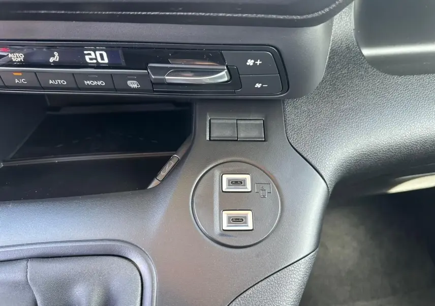 Vue rapprochée du tableau de bord noir du Citroën Berlingo 2026, montrant les commandes de climatisation et deux ports USB-C.