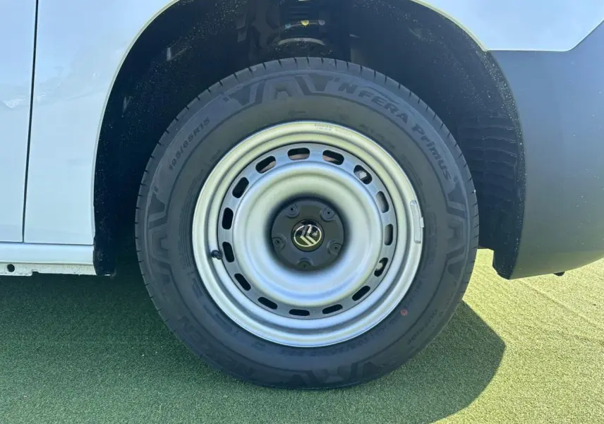 Gros plan sur la roue avant droite en jante tôle grise du Citroën Berlingo blanc Icy, partie basse de la carrosserie visible.