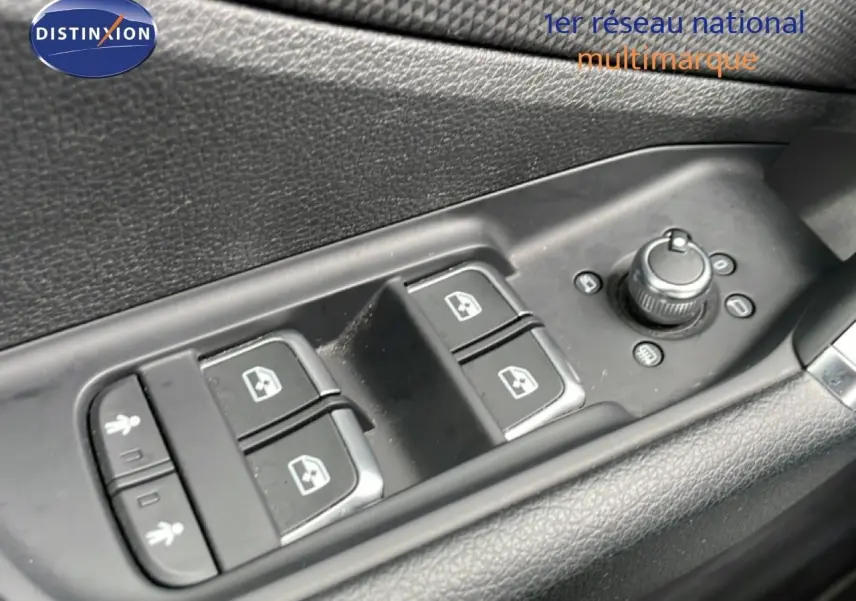 Gros plan sur les commandes des vitres et rétroviseurs côté conducteur d’un Audi Q2 noir mito metal.