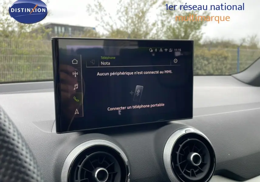 Écran central tactile et aérateurs ronds du tableau de bord d’un Audi Q2 noir mito metal, vue intérieure avant.