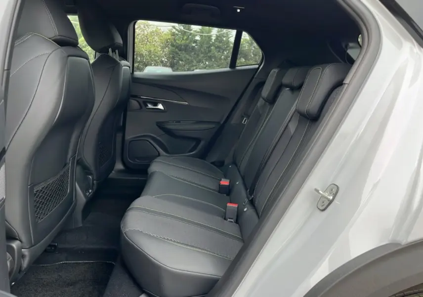 Vue latérale droite de l’habitacle arrière du Peugeot 2008 blanc, avec sièges en cuir noir et surpiqûres vertes.