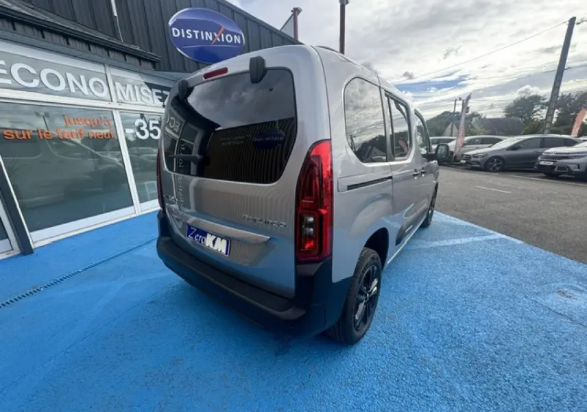 Vue 3/4 arrière droite du Citroën Berlingo gris acier avec vitres arrière teintées et jantes alu noires.