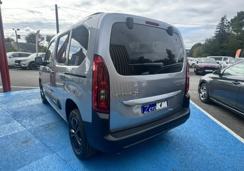 Vue 3/4 arrière droite du Citroën Berlingo gris acier avec vitres arrière teintées et jantes alu noires.