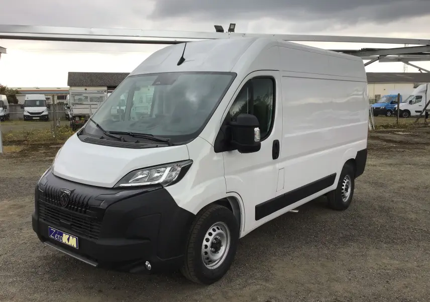 Peugeot Boxer Fourgon blanc vu en 3/4 avant droit, avec pare-chocs noir et calandre marquée.