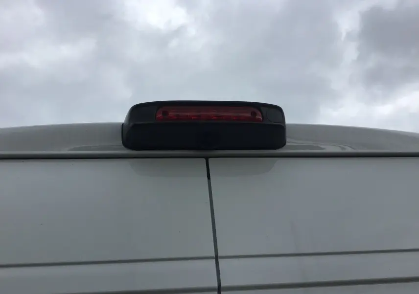 Gros plan sur la caméra de recul et le feu stop supérieur du Peugeot Boxer Fourgon blanc, vue arrière haute.