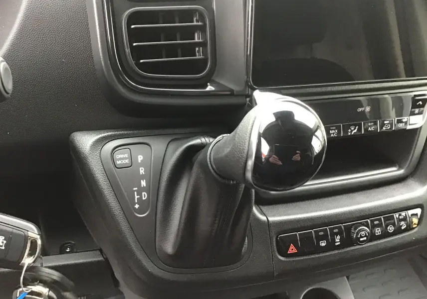 Gros plan sur le levier de vitesses automatique noir et la console centrale du Peugeot Boxer Fourgon blanc, version 2025.