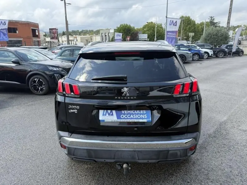 Vue arrière d'un Peugeot 3008 noir 2018 avec feux arrière à griffes et attelage visible sur parking.