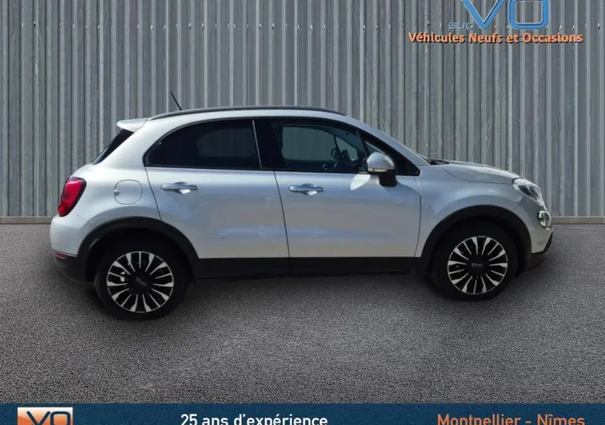 Profil côté gauche d'un FIAT 500X gris clair avec jantes alliage 17 pouces sur fond urbain neutre.
