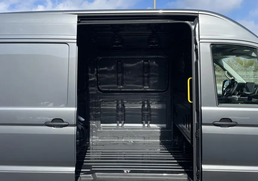 Vue latérale droite du Volkswagen Crafter gris Indium avec porte coulissante ouverte montrant l'espace de chargement vide