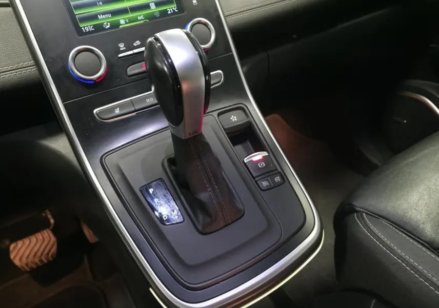 Gros plan sur la console centrale du Renault Scénic blanc 2017, mettant en valeur le levier de vitesse automatique EDC et les commandes adjacentes.