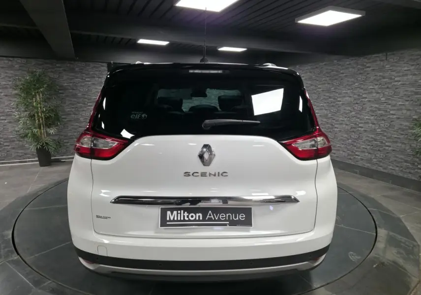Vue arrière d'un Renault Scénic blanc nacré avec toit noir dans un showroom intérieur.