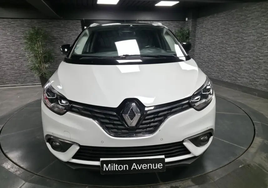 Vue frontale d'un Renault Scénic blanc nacré avec calandre noire et phares Full LED dans un showroom.