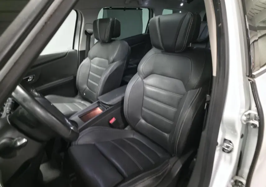 Intérieur vue côté conducteur d'un Renault Scenic blanc avec sièges cuir carbone foncé et accoudoir central.