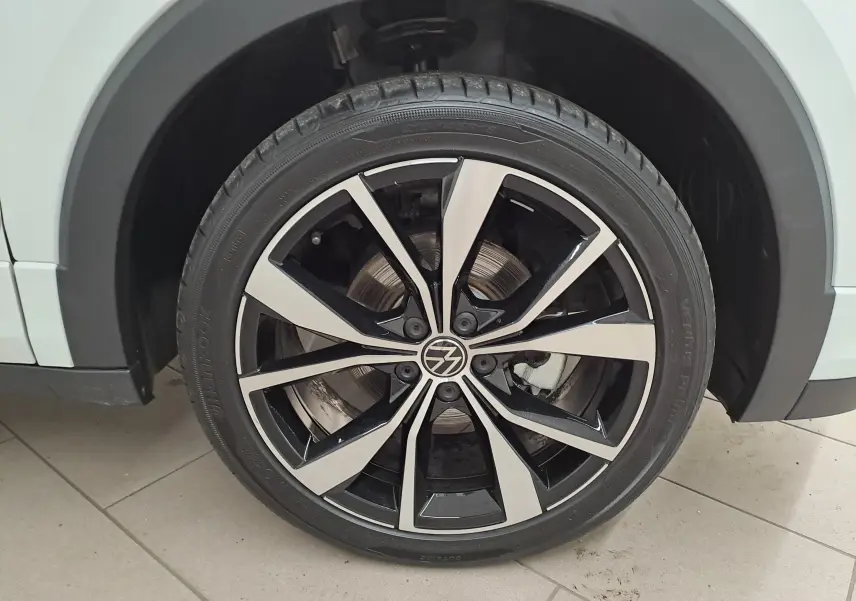 Gros plan sur la roue avant droite du Volkswagen T-Cross blanc Pur 2025 avec jante alliage R-Line bicolore.