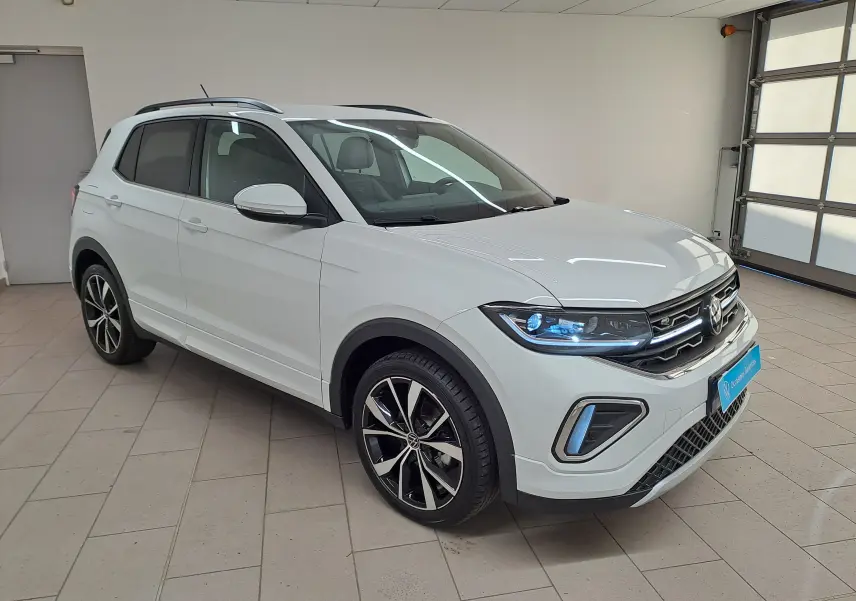 Vue frontale d'un Volkswagen T-Cross blanc pur 2025 avec signature lumineuse LED et calandre R-Line noire.