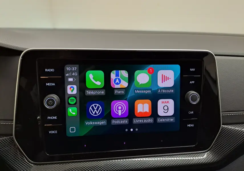 Écran tactile central du Volkswagen T-Cross 2025 blanc, affichant l’interface Apple CarPlay avec icônes colorées.
