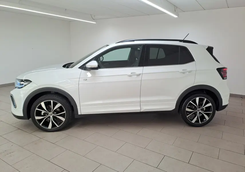 Volkswagen T-Cross 1.0 TSI R-Line blanc pur vu de profil côté gauche en intérieur avec jantes alliage noires et argentées.