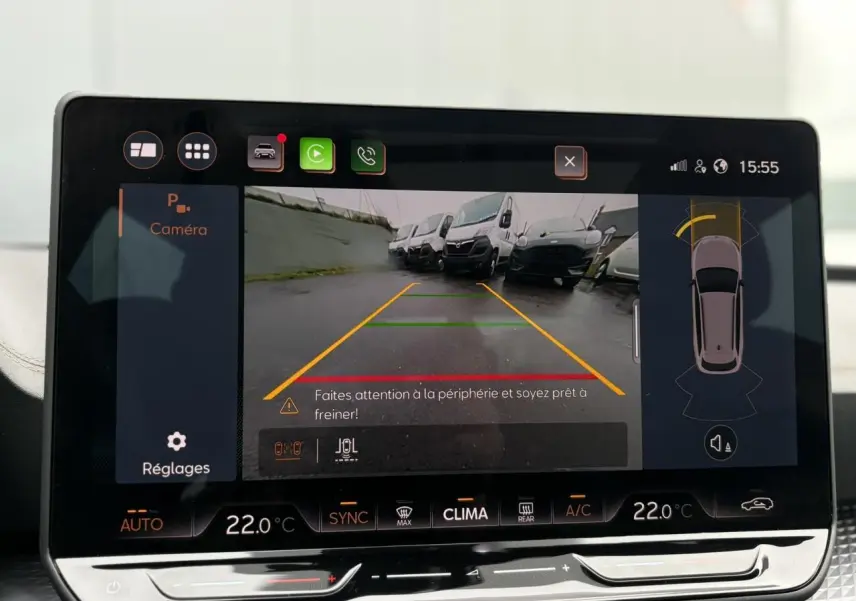 Écran tactile intérieur montrant la caméra de recul avec vue arrière sur un parking, tableau de bord moderne noir.