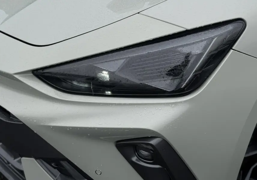 Gros plan sur le phare avant droit gris Taiga de la CUPRA LEON ST 2025 avec pluie et antibrouillard noir.