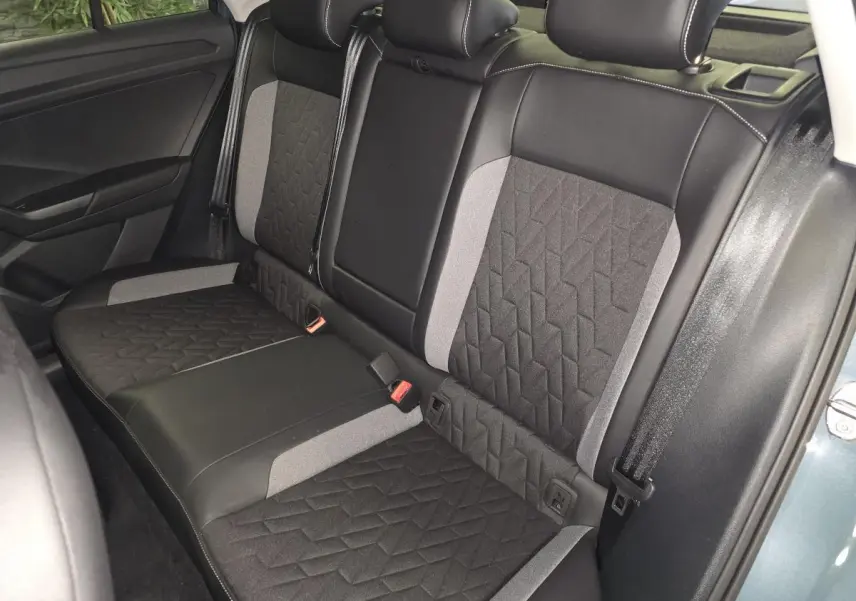 Vue intérieure de la banquette arrière du Volkswagen T-Roc 2025 avec sellerie tissu noir et gris à motifs géométriques.