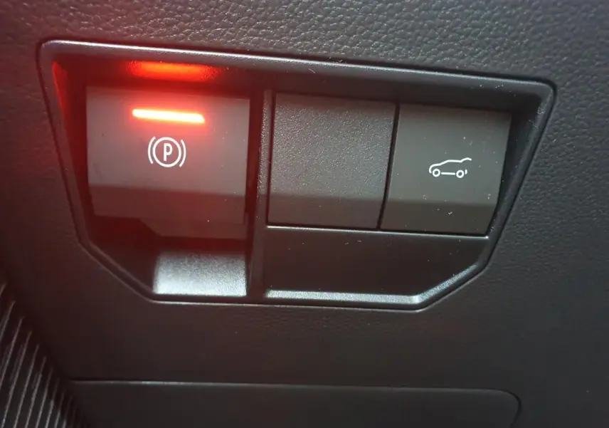 Boutons de commande du frein de parking électrique et ouverture du coffre sur tableau de bord noir du Dacia Bigster.