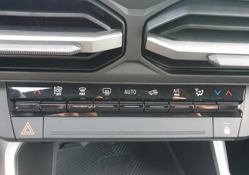 Vue rapprochée du tableau de bord de la Dacia Bigster 2026, montrant les commandes de climatisation automatique et les aérateurs noirs.