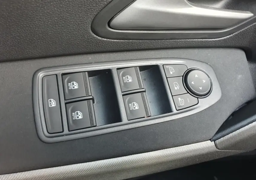 Vue rapprochée des commandes de lève-vitres et rétroviseurs sur la porte côté conducteur d’un Dacia Bigster noir Perla.
