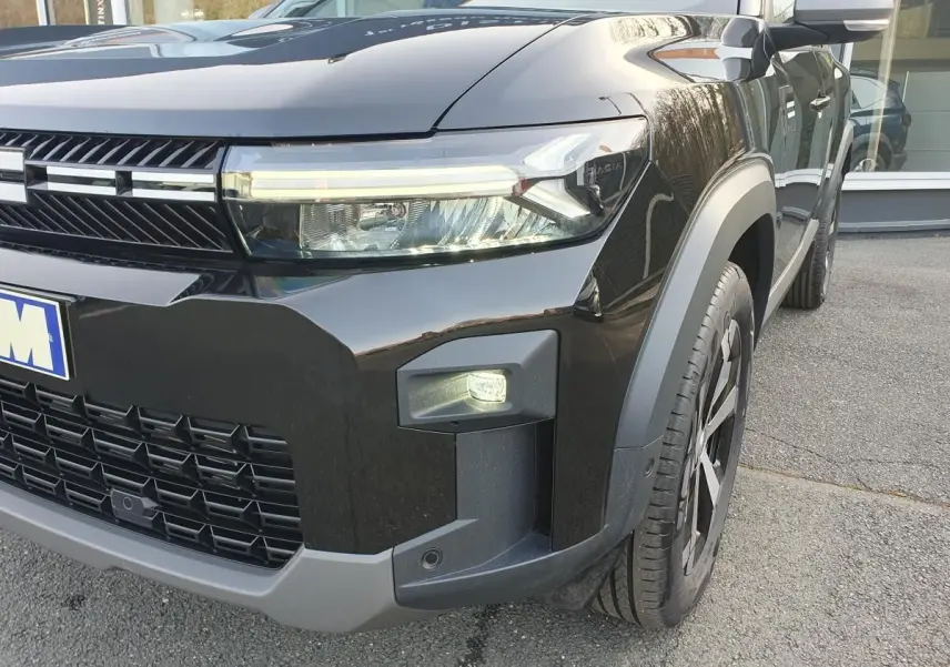 Vue 3/4 avant droit du Dacia Bigster noir Perla avec signature lumineuse LED et jante alliage 18 pouces diamantée.