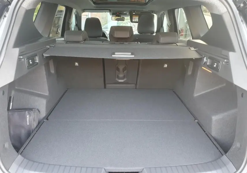 Vue arrière du coffre spacieux du Dacia Bigster noir Perla avec banquette rabattue et cache-bagages déployé.