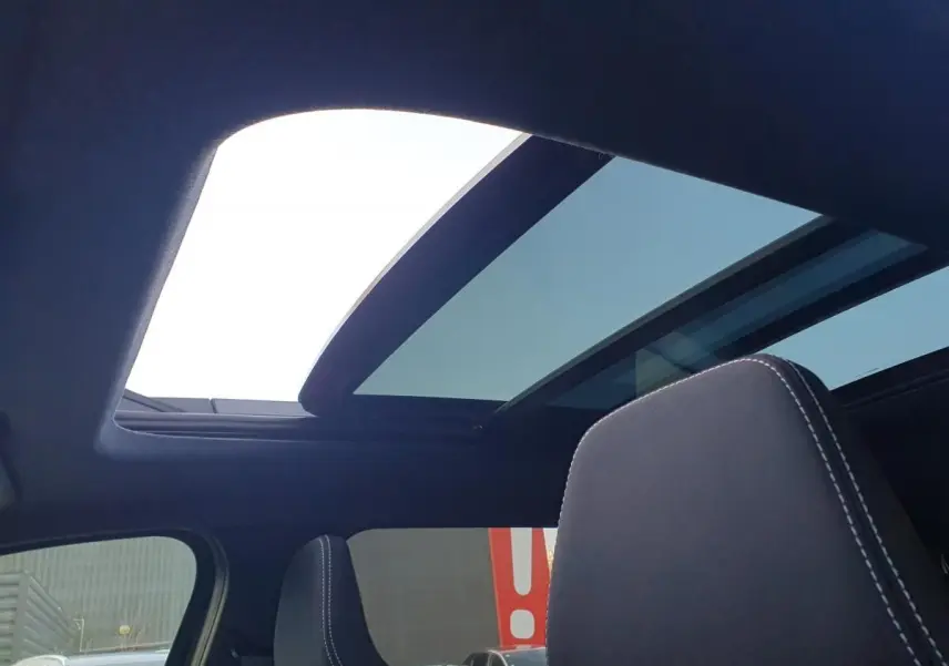 Vue intérieure du toit panoramique ouvert du Dacia Bigster noir Perla, avec appui-tête avant visible.