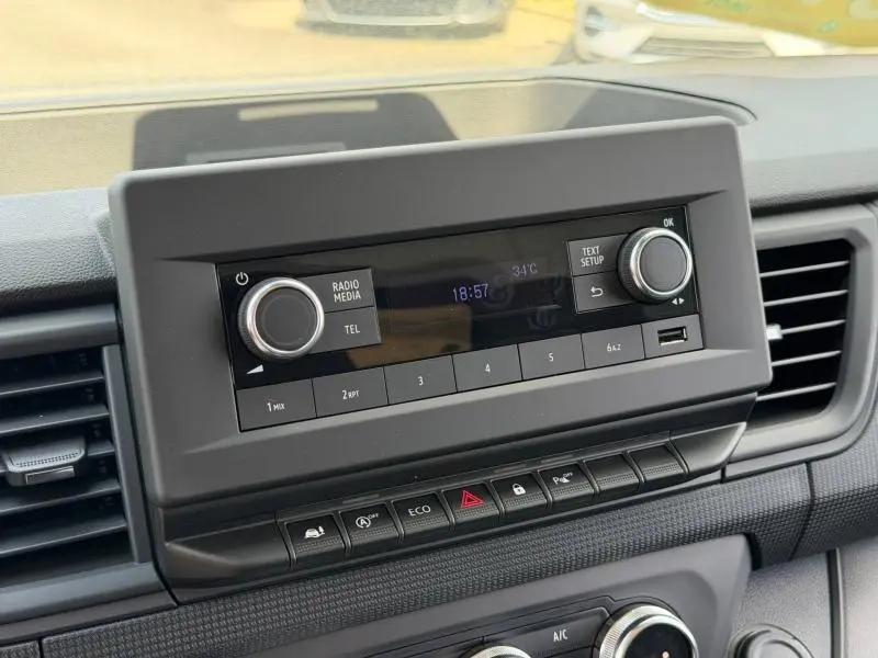 Gros plan sur l’écran tactile et la console centrale du Renault Trafic Fourgon blanc, avec commandes radio et climatisation visibles.