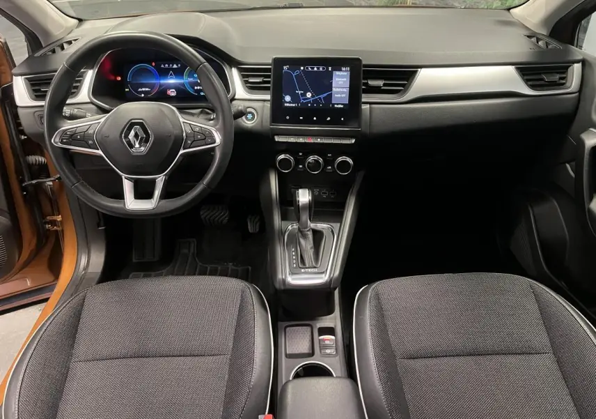 Vue intérieure avant du Renault Captur orange 2022, tableau de bord moderne avec écran tactile et volant multifonction noir.