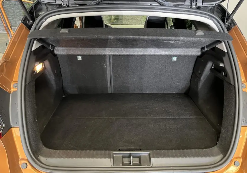 Coffre ouvert vu de l'arrière d'un Renault Captur orange 2022 avec cache-bagages et intérieur noir.