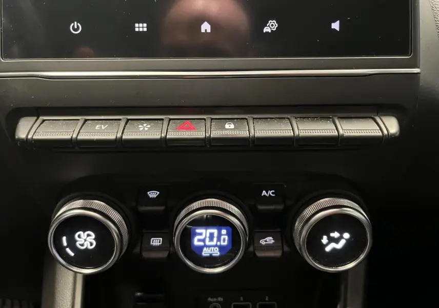 Gros plan sur la console centrale noire du Renault Captur 1.6 E-Tech Hybride avec commandes climatisation et boutons fonctionnels.