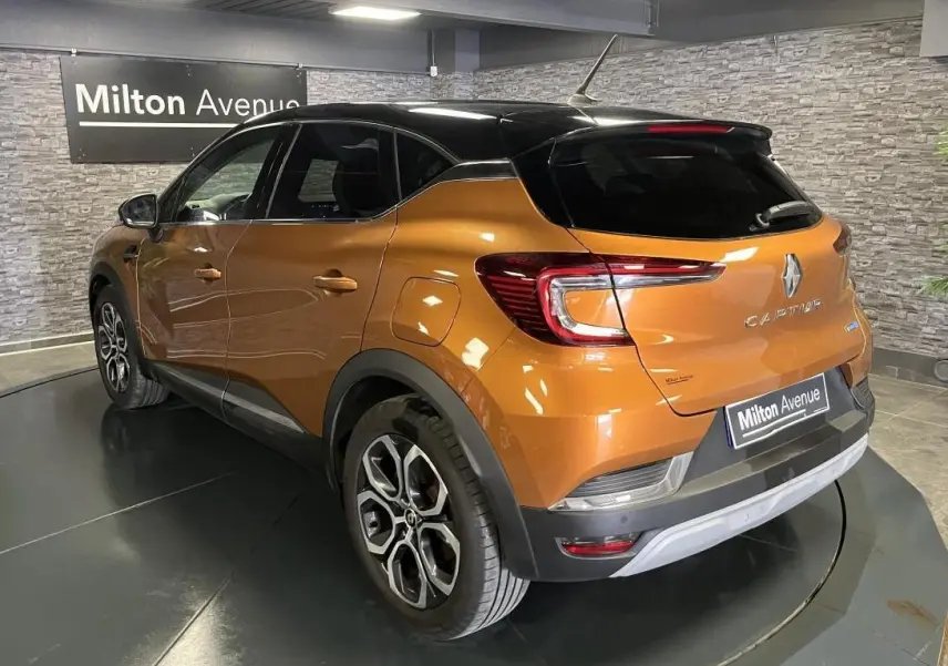 Vue 3/4 arrière droite du Renault Captur 1.6 E-Tech hybride rechargeable orange avec toit noir et jantes alliage.