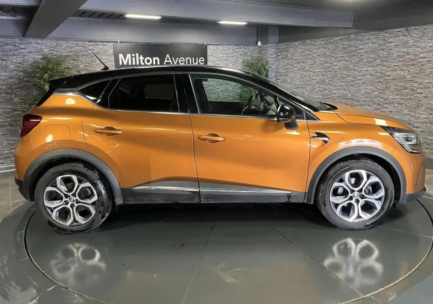 Profil droit d'un Renault Captur orange 2022 avec toit noir et jantes alliage 18 pouces Pasadena diamantées.