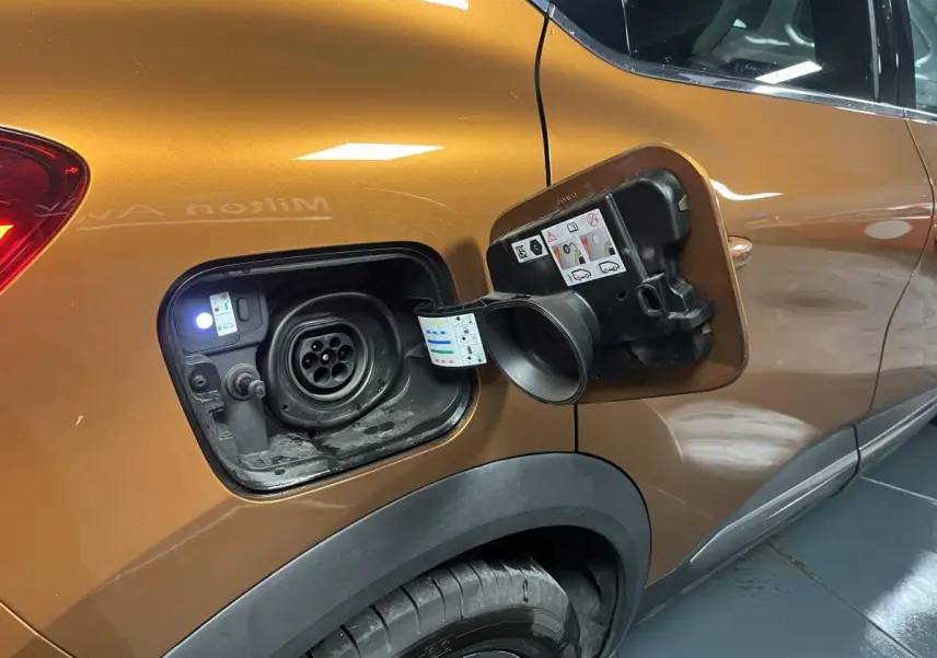 Prise de recharge ouverte côté gauche d’un Renault Captur orange 2022 hybride rechargeable avec peinture bi-ton.